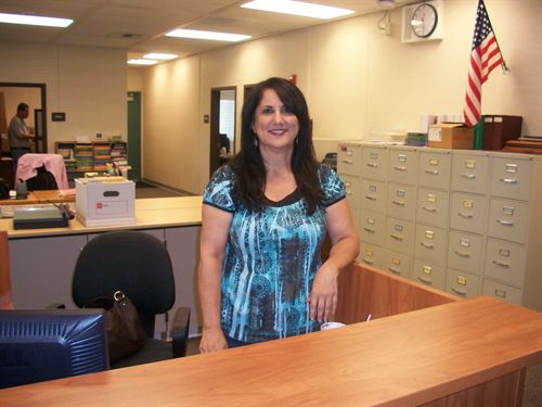 female staff standing a desk with left arm leaning on desk rail